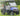 TrailMaster Taurus 50EV 4-seat electric golf cart in blue, featuring 60V motor, off-road tires, and LED headlights, on green grass.