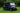 TrailMaster Taurus 80ED-GV 6-seat electric golf cart with an extended roof, shown on grass with a sleek black design.