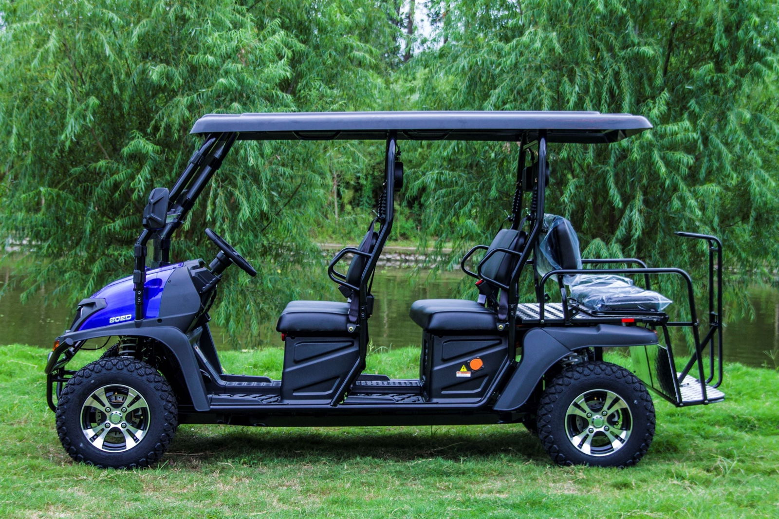 TrailMaster Taurus 80ED-GV 6-seat electric golf cart with an extended roof, ideal for beach outings, shown in a lush outdoor setting.