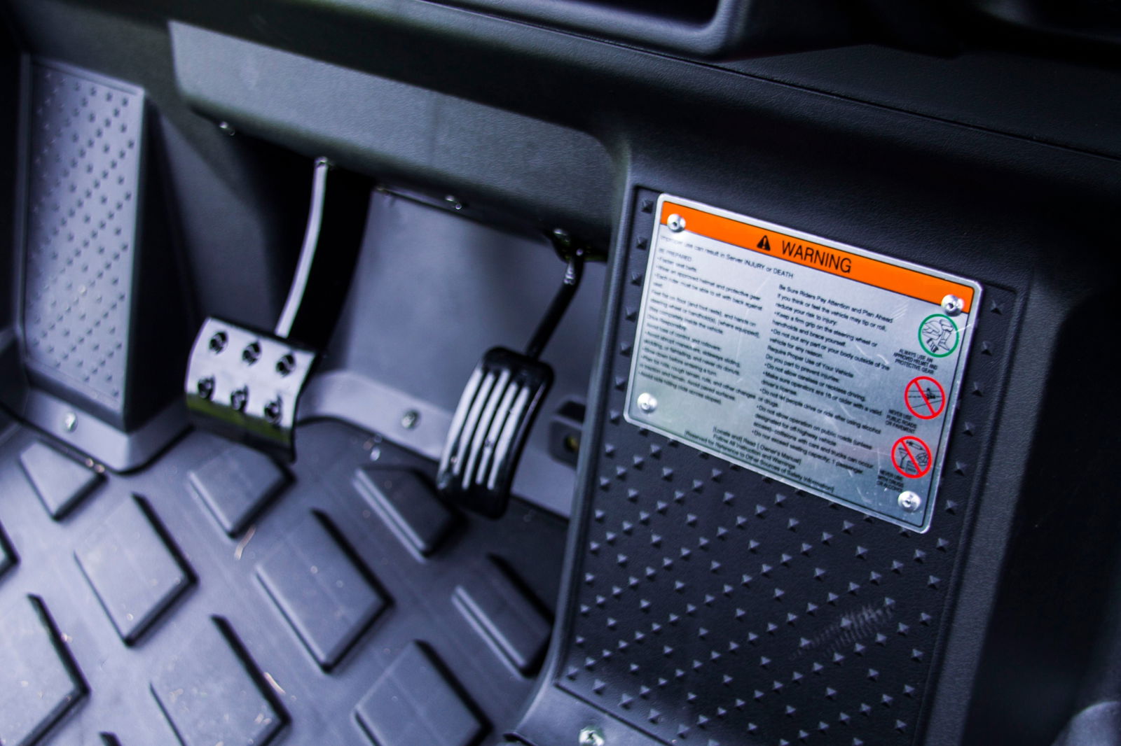Interior view of TrailMaster Taurus 80ED-U electric golf cart showcasing pedals and warning sticker on the floor panel.